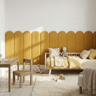 Ein gemütliches Kinderzimmer mit Holzbett, gelber Bettwäsche, Teddybär, flauschigem Teppich, Holztisch und -stuhl, Bücherregalen, verstreutem Spielzeug und Bauklötzen, dazu ein einzigartiges KraftKids Wandpaneel abgerundetes Doppelkrepp im Rundbogen-Design.