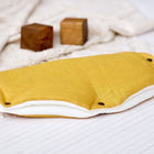 Der KraftKids Kinderwagenmuff Leinen gelb senfgelb ist ein handgenähter gelber, rechteckiger Stoffwärmer mit schwarzen Druckknöpfen, der auf einem cremefarbenen Tuch in der Nähe von Holzklötzen abgebildet ist - perfekt für Ihren Kinderwagen.