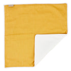 Die KraftKids Wickelunterlage Leinen gelb senfgelb ist eine rechteckige, senfgelbe Wickelunterlage mit weißem Rand, die zusammengefaltet ihre weiche weiße Unterseite und ihr Stoffetikett zeigt - ideal als wasserundurchlässige Unterlage für unterwegs.