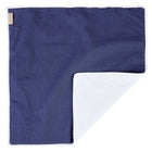 Die KraftKids Wickelunterlage Leinen blau dunkelblau hat eine rechteckige Form mit einer dunkelblauen Oberseite und einer hellgrauen Unterseite. Sie ist an einer Ecke ordentlich gefaltet, so dass beide Farben vor einem weißen Hintergrund zu sehen sind.