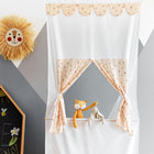 Ein gemütliches Kinderzimmer mit dem KraftKids Puppentheater Kasperletheater Musselin Kirschen inkl.. Teleskopstange und zwei Tierpuppen, dazu eine Löwenwanddekoration und eine Kreidetafel mit bunter Kunst und "Zoe" auf der grauen geometrischen Wand.