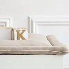 Zwei Holzklötze, einer mit K, sitzen auf der beigen Wickelauflage Musselin von KraftKids vor einer weißen Wand mit Zierleiste - ein eleganter Akzent für jeden Wickelplatz.