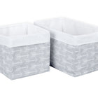 Zwei rechteckige KraftKids Körbchen "weiße Pfeile auf Grau" aus Baumwolle, nebeneinander platziert. Die Aufbewahrungskörbe haben weiße Innenflächen, graue Außenflächen mit weißen Pfeilen und oben einen umgeschlagenen weißen Rand.