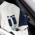 A KraftKids Decke für Babyschale Winter Musselin in dunkelblau mit weißen Anker-Motiven liegt auf dem Autositz, wobei der Gurt der Babyschale über der Decke sichtbar ist.