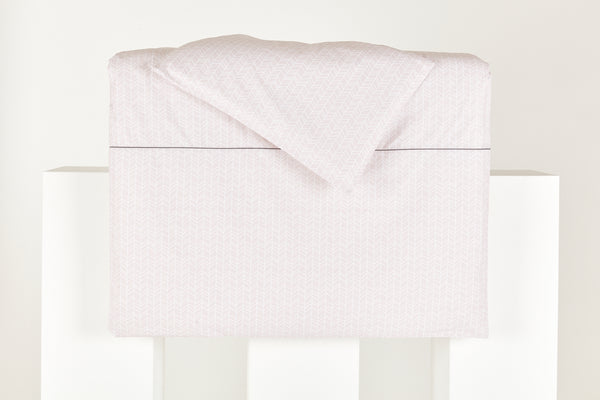 Das KraftKids Bettwäscheset "weiße Feder Muster auf Rosa" liegt ordentlich gefaltet auf einer weißen Fläche und präsentiert sich mit seiner hellrosa Farbe und dem zarten Federmuster vor einem schlichten weißen Hintergrund.