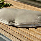 Der KraftKids Kinderwagenmuff Leinen Natur Braun, ein hellbrauner und weißer handgenähter Leinenmuff mit Druckknöpfen, ruht auf einer Holzlattenbank im Grünen.