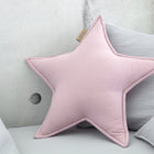 Das KraftKids Sternkissen Doppelkrepp Rosa, ein weiches sternförmiges Kissen in Hellrosa, liegt auf einem hellgrauen Sofa mit anderen Kissen. Eine Betonwand mit einem runden Loch im Hintergrund verleiht jedem Kinderzimmer Charme.