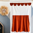 A KraftKids Puppentheater Kasperletheater Doppelkrepp Rot Herbstrot mit Teleskopstange hängt vor einer geometrischen Wand. Ein Stroh-Löwengesicht und ein Teil einer Tafel mit "Zoe" sind ebenfalls zu sehen.