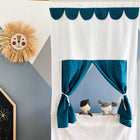 Das KraftKids Puppentheater Kasperletheater Musselin mit goldenen Punkten auf Petrol und Teleskopstange steht vor einer grau-weißen Wand. Zwei Stoffpuppen spielen, links sind ein Stroh-Löwengesicht und eine bemalte Tafel zu sehen.