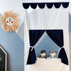 Das KraftKids Puppentheater Kasperletheater Musselin dunkelblau Anker inkl. Teleskopstange mit blauen Vorhängen steht vor einer geometrischen Wand; zwei Handpuppen spielen, während eine Strohsonne und bunte Kreidezeichnungen die Szene schmücken.